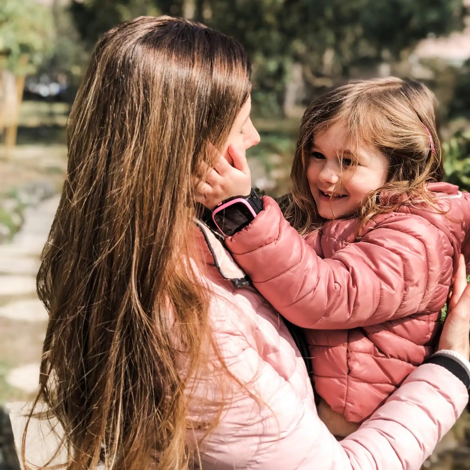 Un moment tendre entre un parent et un enfant portant des manteaux d'hiver roses assortis.